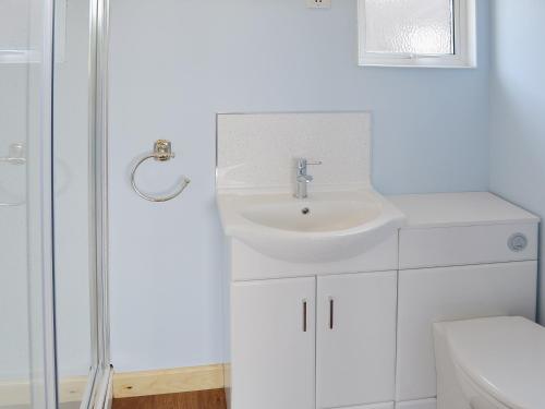 a white bathroom with a sink and a shower at High Tide - 30259 in Cromer
