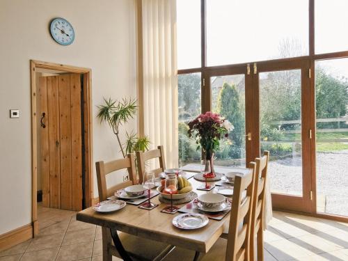 uma sala de jantar com uma mesa de madeira com cadeiras e um relógio em The Granary - E5483 em Froghall