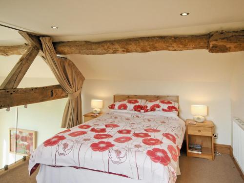 um quarto com uma cama com flores vermelhas em The Granary - E5483 em Froghall