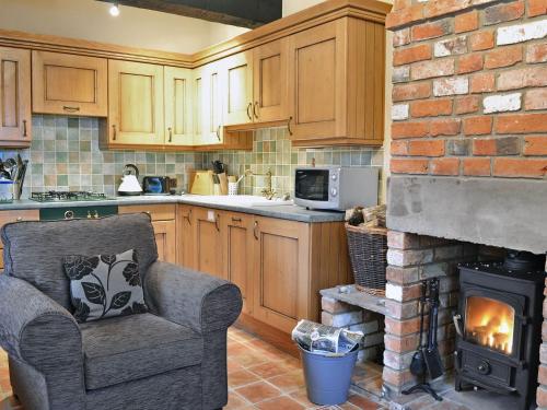 a kitchen with a chair and a brick fireplace at The Stable - Ijx in Brigham