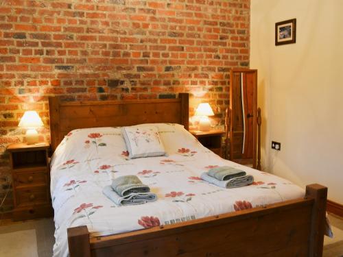 a bed in a room with a brick wall at The Stable - Ijx in Brigham