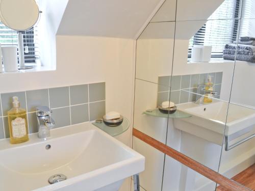 a white bathroom with a sink and a mirror at The Cottage in Stroud