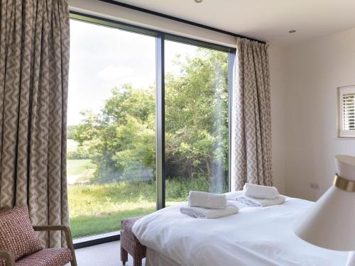 a bedroom with a bed and a large window at The Cotswold Barn in Ampney Crucis