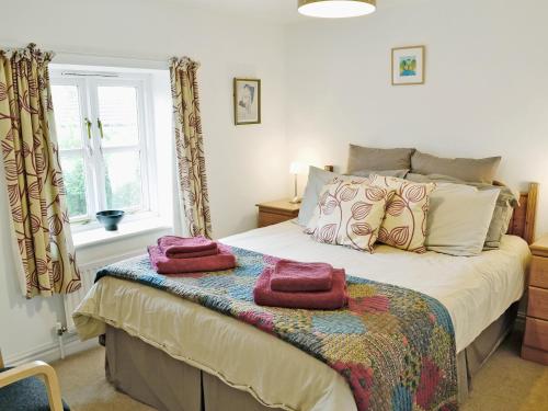 Meadow Cottage-e1793 في Broadwindsor: غرفة نوم عليها سرير وفوط