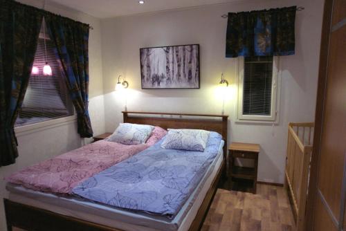 ein Schlafzimmer mit einem Bett und zwei Fenstern in der Unterkunft Villa Mustikkakumpu in Sonka