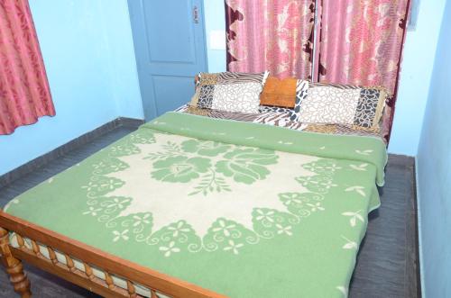 Una cama con una manta verde y blanca. en AARRAAMS Farms & Resorts, en Masinagudi