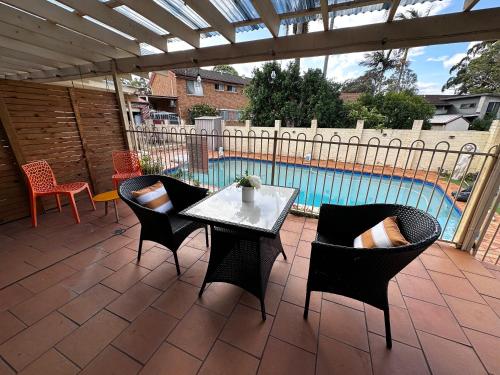 eine Terrasse mit einem Tisch, Stühlen und einem Pool in der Unterkunft 2 bedroom retreat with Swimming Pool in Baulkham Hills