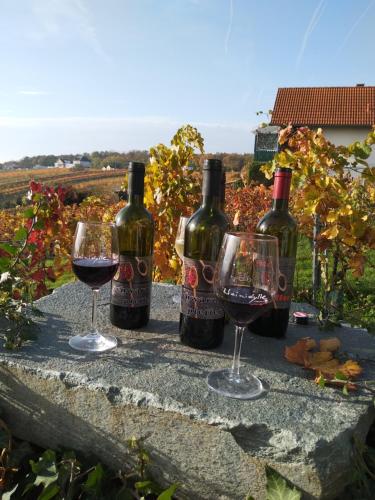 3 bouteilles et 2 verres de vin sur un mur en pierre dans l'établissement Ferienhaus Szapary I, à Eisenberg an der Pinka