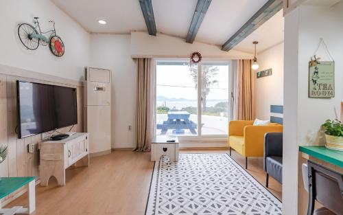 sala de estar con TV de pantalla plana y sofá en Soulmate Pension, en Namhae