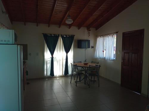 a dining room with a table and chairs and windows at Cabañas Quinco in Merlo