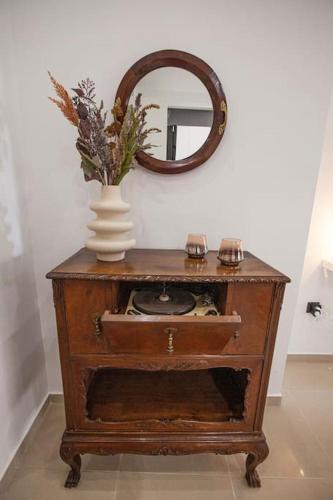 a vase of flowers on a table with a mirror at Kalafatis Downtown Apartment in Itea