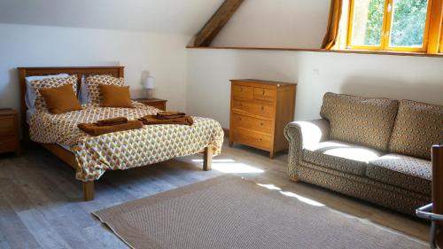 Villas de Leypinas B&B في Saint-Pardoux-Corbier: غرفة نوم بسرير واريكة وكرسي