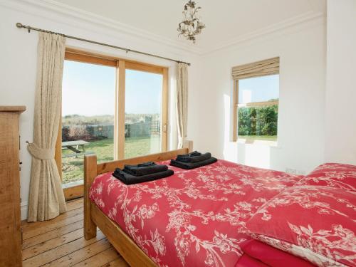 a bedroom with a red bed and a window at Glan Y Mor 1 in Trearddur