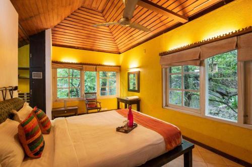 a bedroom with a large bed in a room with windows at Mystic Mayapott, Thekkady in Thekkady
