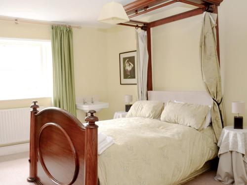 a bedroom with a bed with a wooden canopy at Abbotts Farm in Horbling