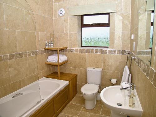 a bathroom with a toilet and a sink and a tub at Rising Sun Holiday Cottage in Aldwark