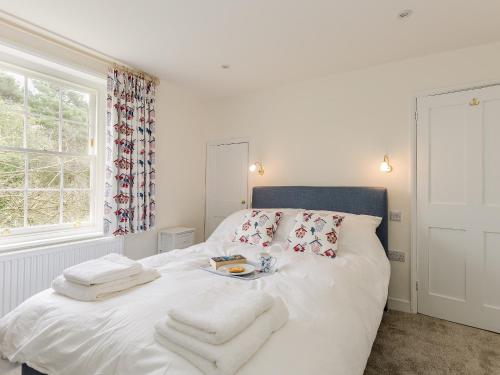 a bedroom with a white bed with towels on it at Pond Cottage in Boldre