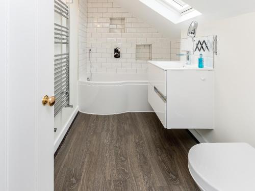 a bathroom with a white tub and a toilet and a sink at Pond Cottage in Boldre