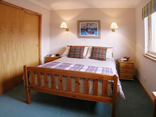 a bedroom with a wooden bed in a room at Rowan Cottage in Carrbridge
