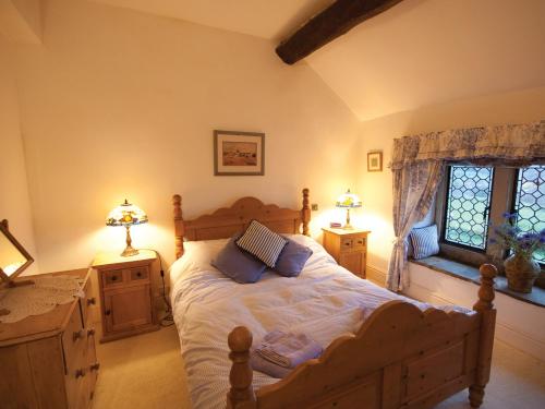 キャッスルトンにあるMullions Cottageのベッドルーム1室(ベッド1台、ランプ2つ、窓付)