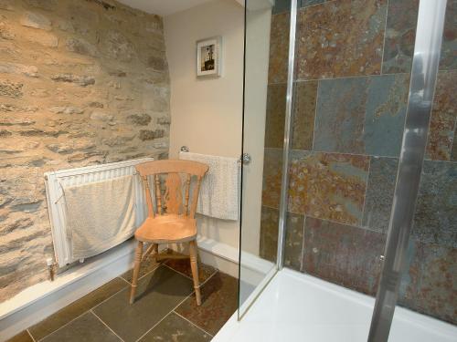 a shower with a wooden chair in a bathroom at The Old Forge in Kingston