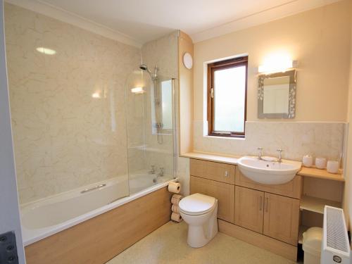 a bathroom with a sink and a toilet and a tub at Nautical Nook in Stalham