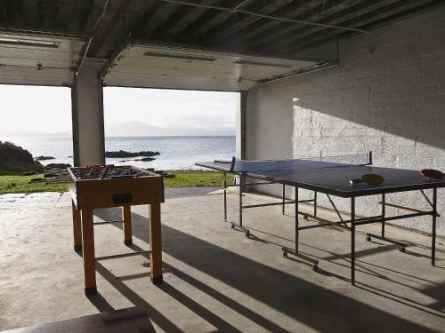 a ping pong table in a room with a view of the ocean at South Bay Cottage in Saasaig