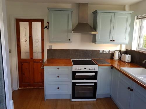 a kitchen with white cabinets and a stove top oven at Atlantic Retreat - 5 minute stroll from the beach in Bude