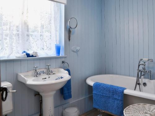 uma casa de banho azul com um lavatório e uma banheira em Harbour Cottage em Winterton-on-Sea