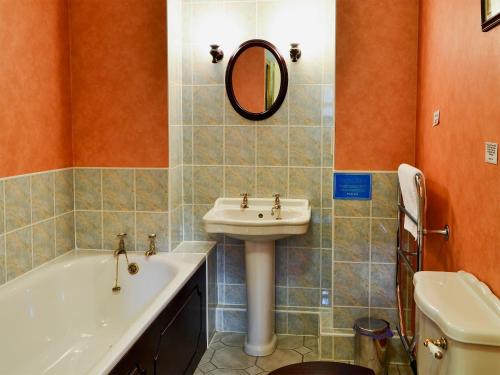 a bathroom with a sink and a tub and a mirror at Busy Lizzie Cottage-mfo in Akeld