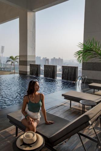 a woman sitting on a table next to a pool at Courtyard by Marriott Navi Mumbai in Navi Mumbai
