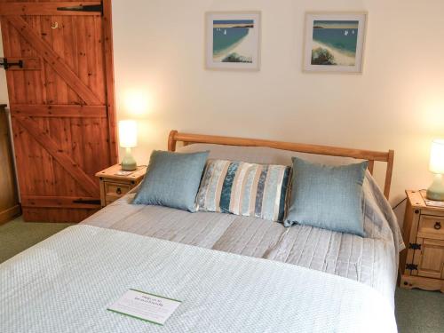 Bruces Cottage في Saint Erth: غرفة نوم مع سرير مع مواقف ليلتين ومصباحين
