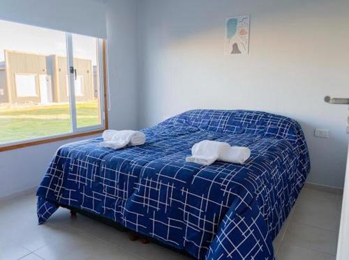 1 cama azul y blanca en una habitación con ventana en primitivo complejo en Comandante Luis Piedra Buena