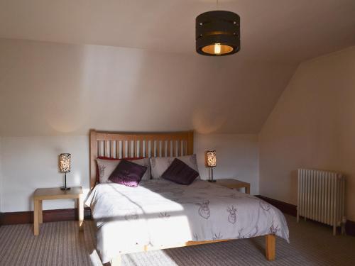 a bedroom with a bed with two tables and two lamps at Garden Cottage in Weem