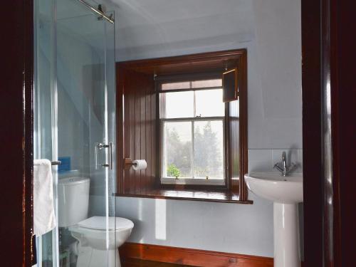 a bathroom with a toilet and a sink and a window at Garden Cottage in Weem