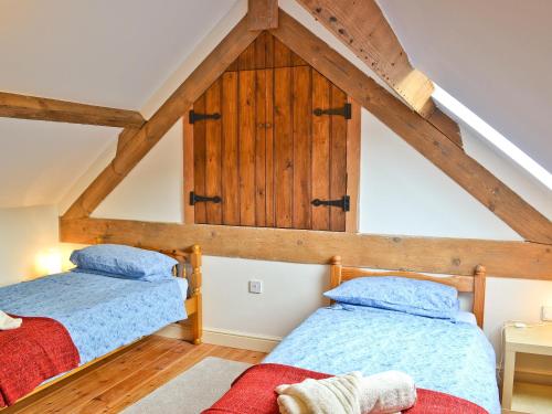 two beds in a attic room with wooden ceilings at The Cobbles in West Pennard