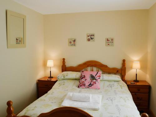 a bedroom with a bed with two night stands and two lamps at Hen Ysgubor - 29518 in Fairbourne