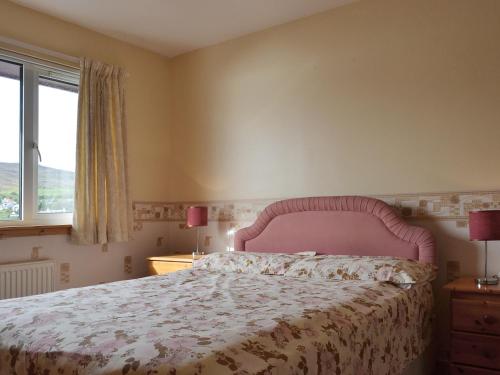 a bedroom with a bed with a pink headboard and a window at Shore View in Portree