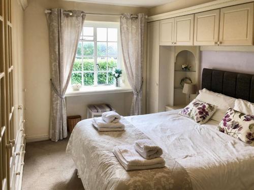 a bedroom with towels on a bed with a window at Laurel Cottage in Stoke Gabriel