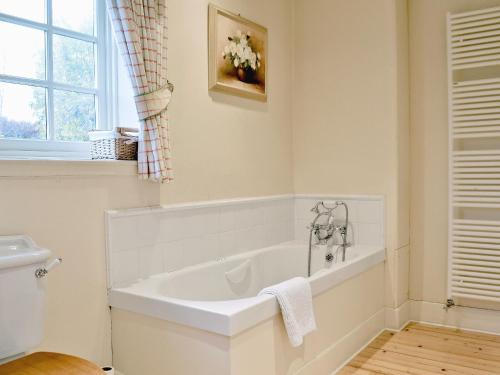 a white bath tub in a bathroom with a window at Dalbeathie Cottage in Birnam