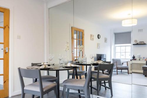 a dining room with a table and chairs and a mirror at Urban Hyde Park One-Bedroom Retreat in London