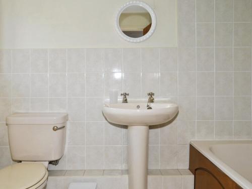 a bathroom with a sink and a toilet and a mirror at Honey Acre Cottage - E2379 in Banwell