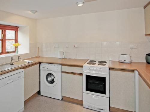 een keuken met een wit fornuis bovenoven naast een gootsteen bij Honey Acre Cottage - E2379 in Banwell