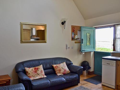 a living room with a leather couch and a mirror at Jasmine Cottage - 30503 in West Firle