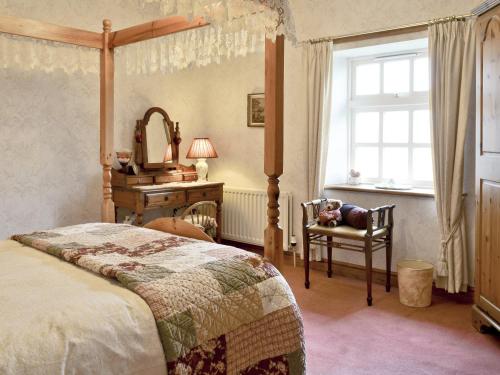 a bedroom with a bed and a chair and a mirror at Rose Cottage - Lpd in Ireby