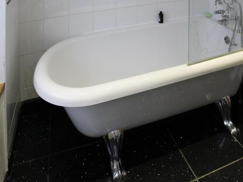 a white bath tub in a bathroom with black tiles at Glaramara in Kendal