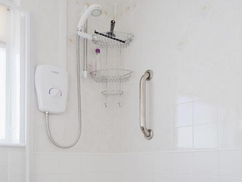 a shower in a white bathroom with a shower head at Avalon in Grainthorpe