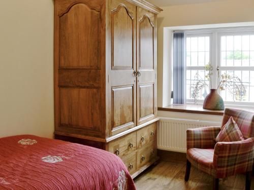a bedroom with a large wooden cabinet next to a window at Lily Vale Cottage in Hendy