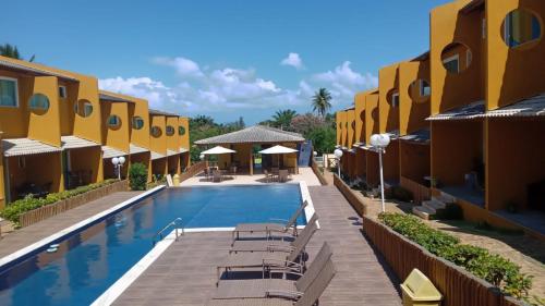 einen Pool mit Stühlen und Sonnenschirmen in einem Resort in der Unterkunft Casa agradável em condomínio perto da praia. in Mata de Sao Joao
