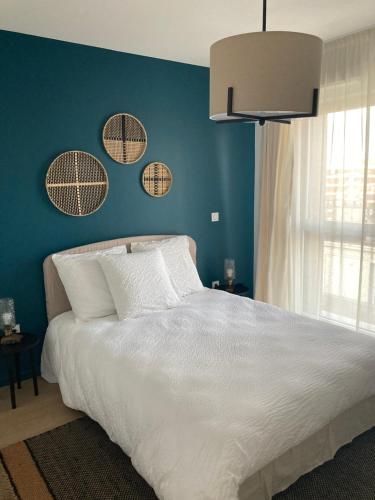 une chambre avec un lit blanc avec un mur bleu dans l'établissement Résidence Services CAZAM, à Clermont-Ferrand